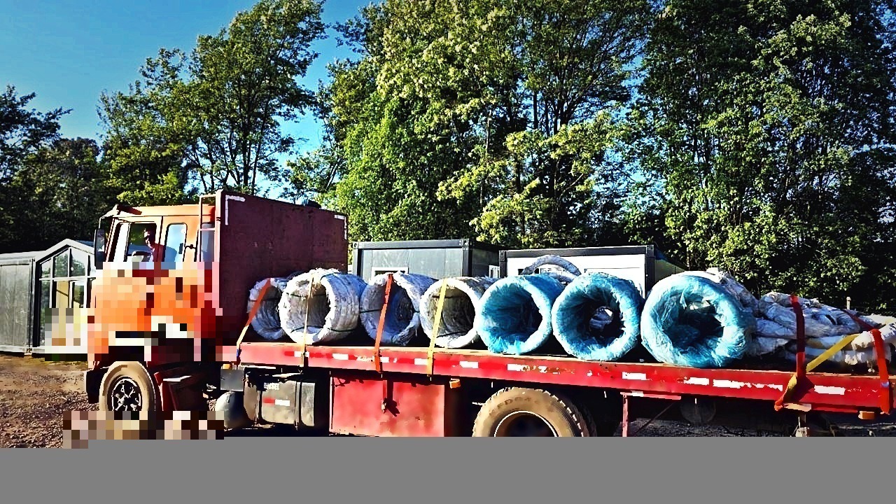 Camión plataforma transportando rollos de alambre para instalaciones agrícolas